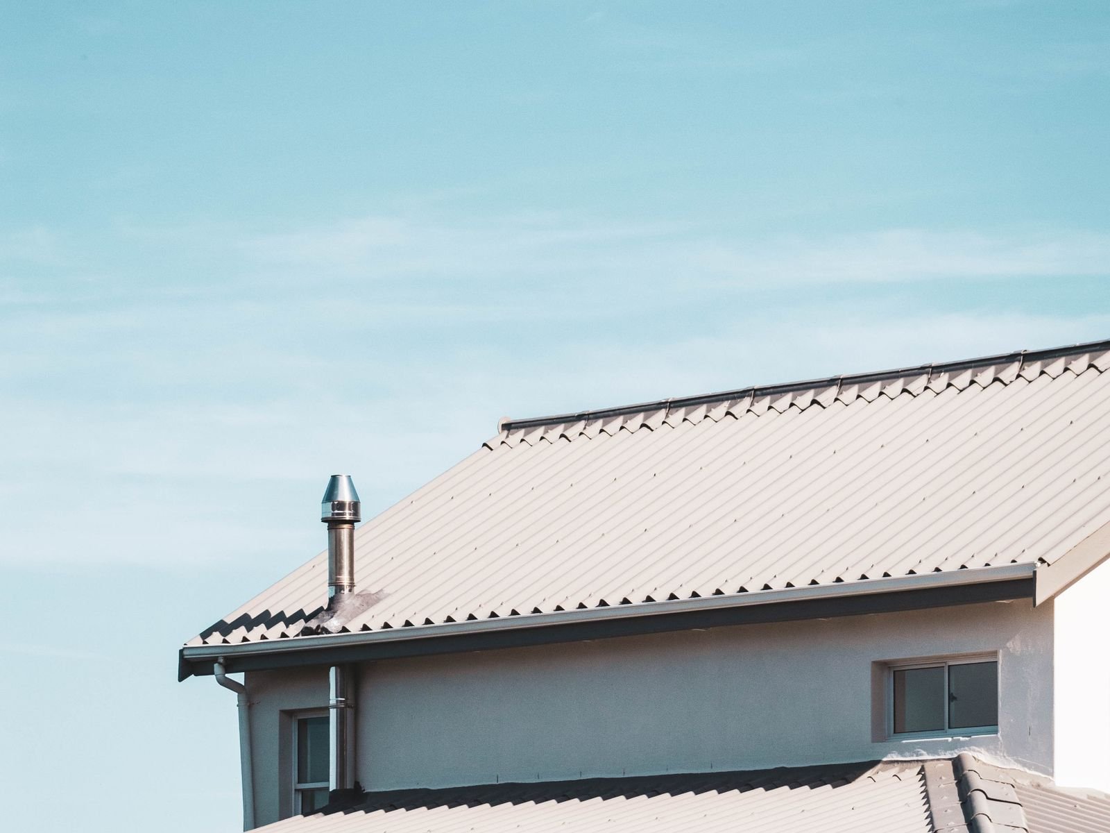 Clean roofline with tiled roof and fascia against a blue sky