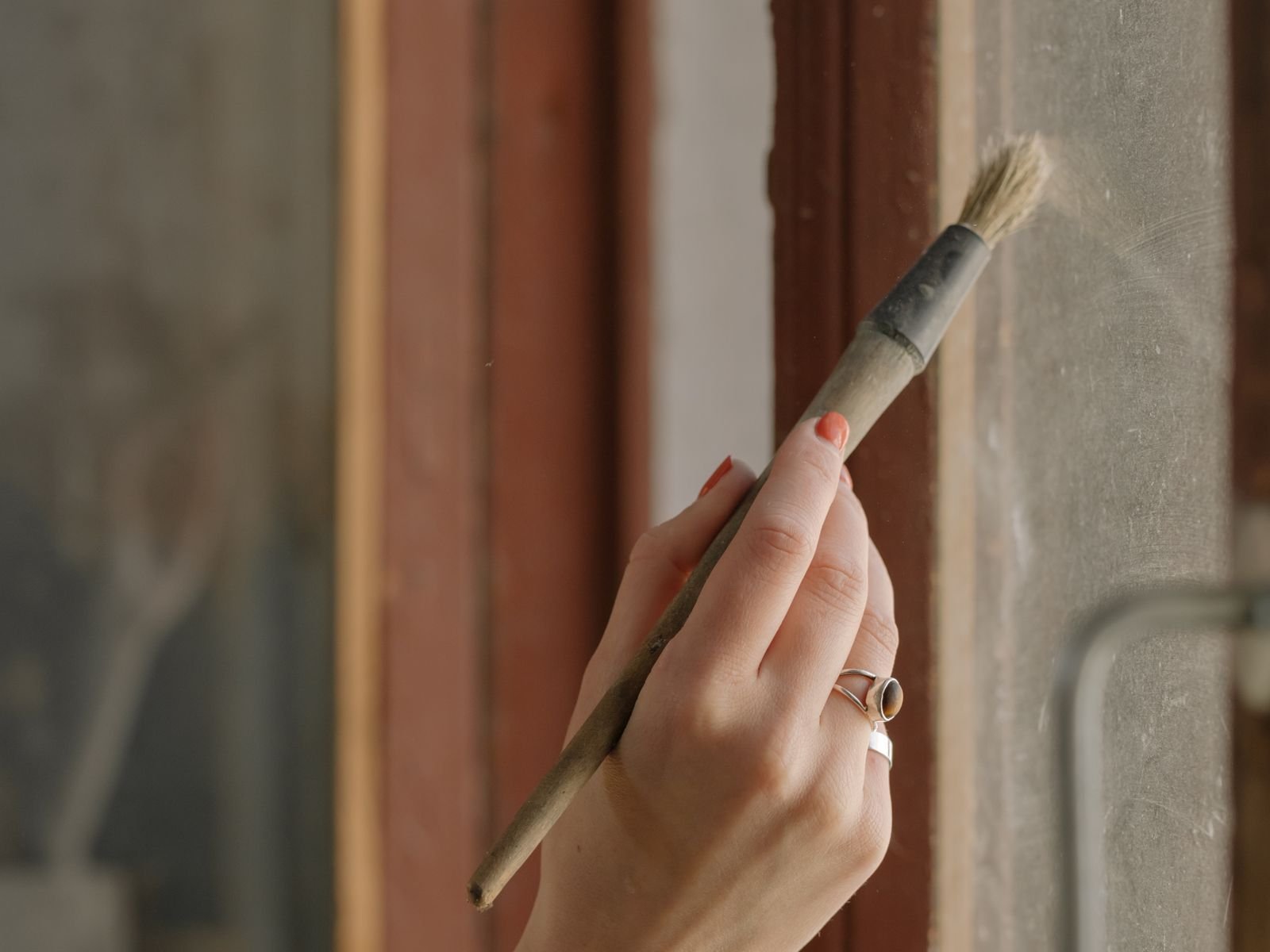 Brush in hand, cutting in around a wooden window frame
